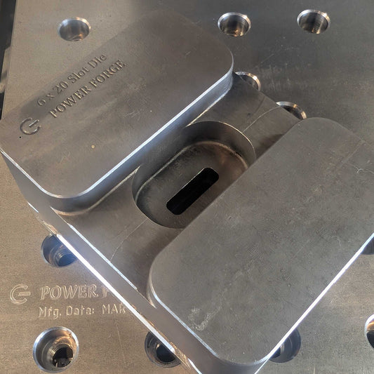 Metal component with 'Power Forge' branding on a workshop surface