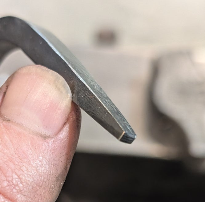 Close-up of a hand holding a metal tool against a blurred background