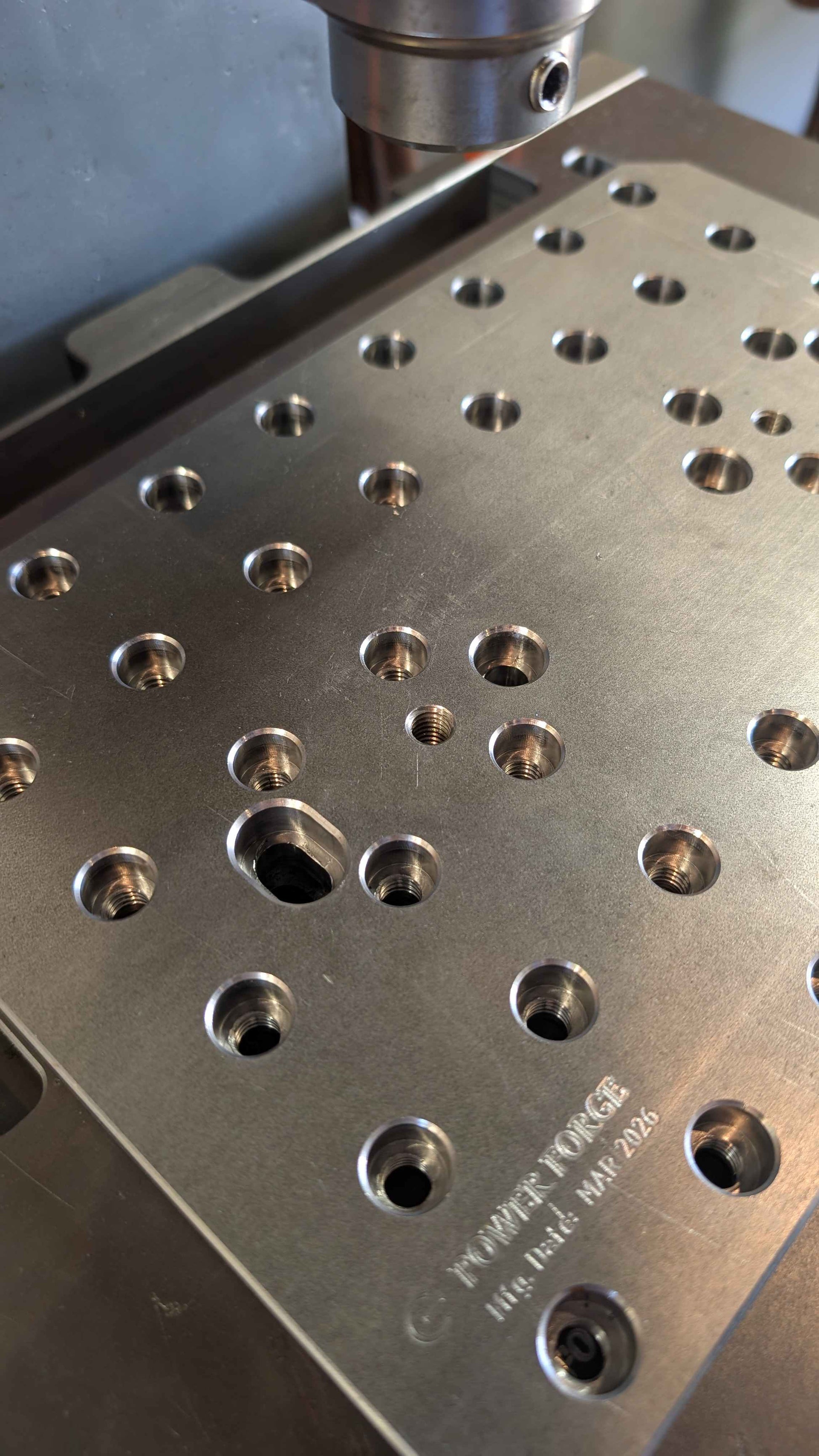 Metal plate with holes and engraved text on a machine.