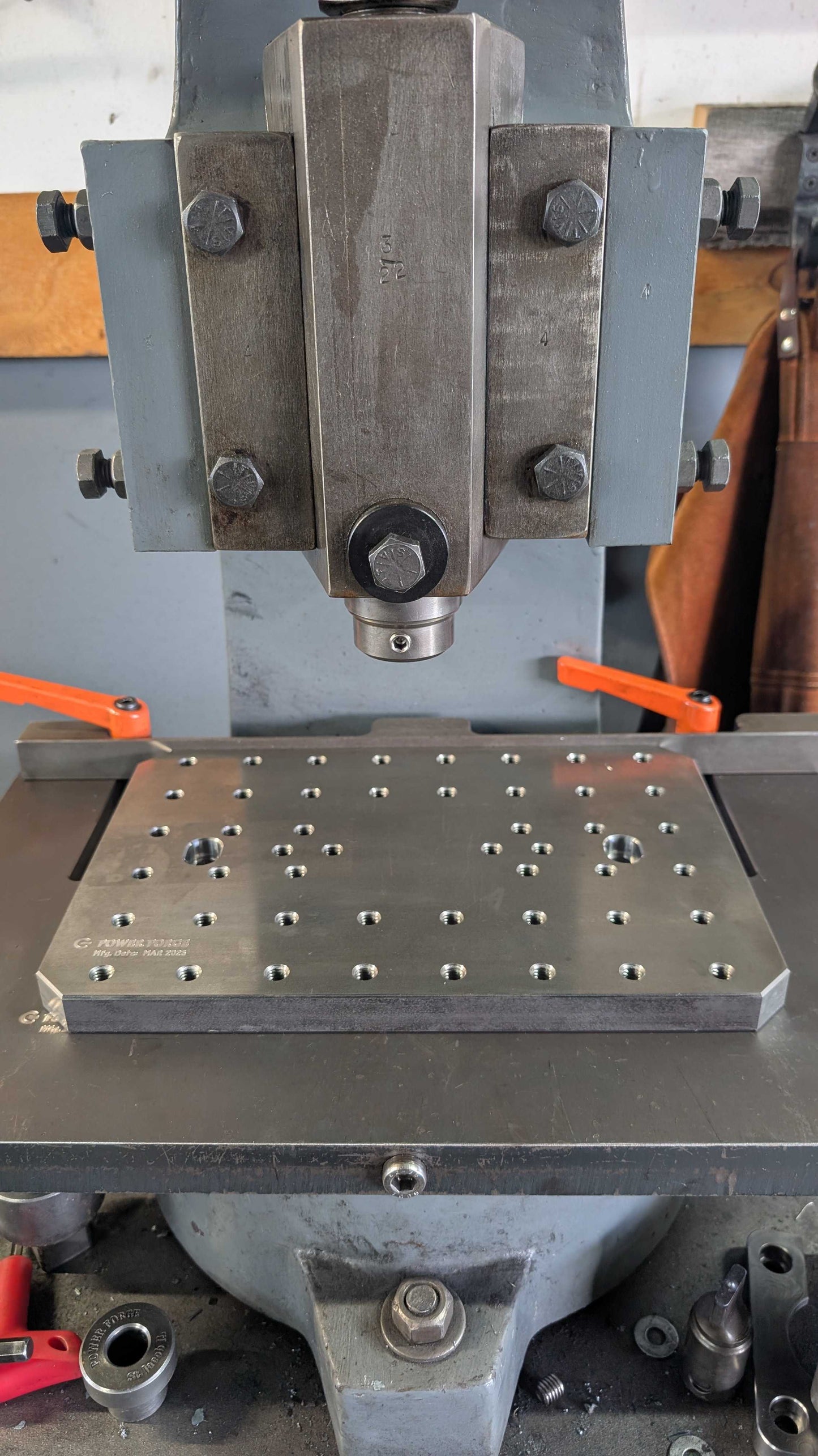Metalworking machine with a flat metal plate and bolts on a workshop background