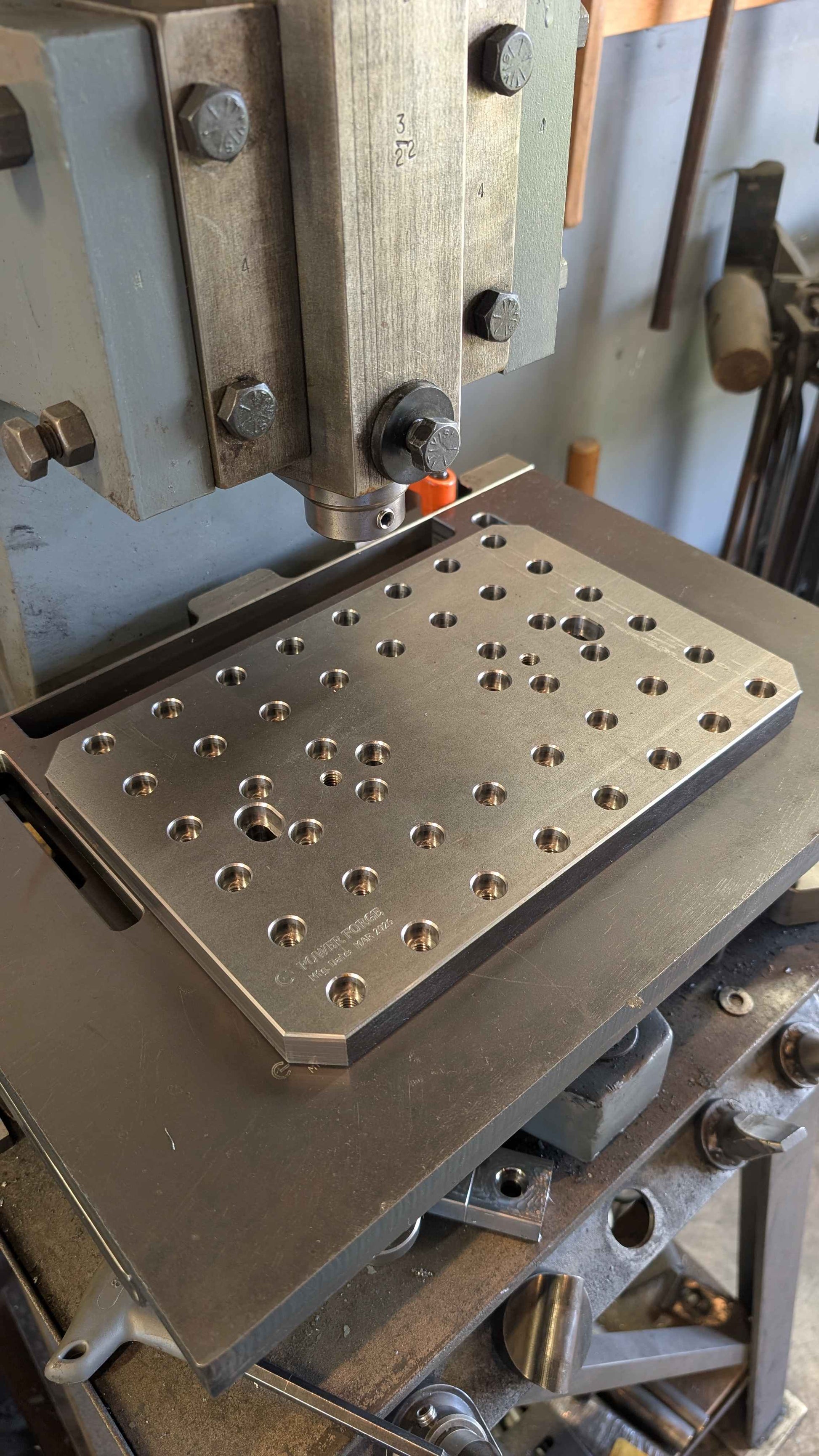 Metalworking machine with a plate featuring holes in a workshop setting