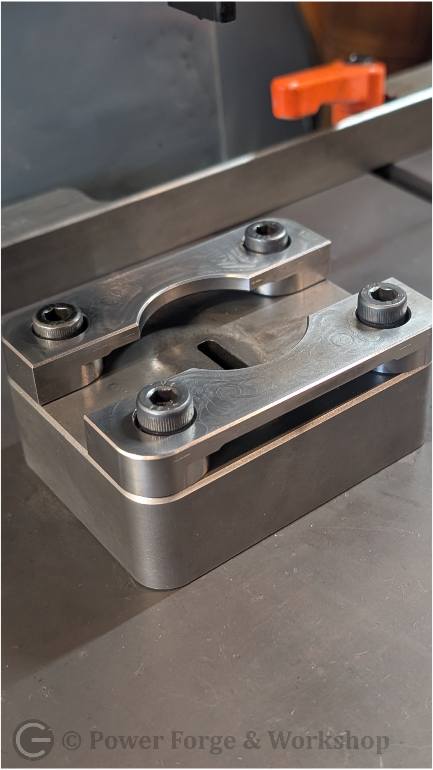 Metal component on a machine with 'Power Forge & Workshop' branding